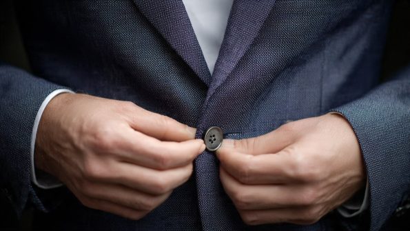 A Person Buttoning The Bottom Button